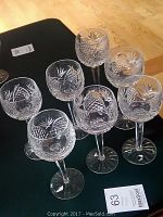 Seven crystal wine glasses arranged on table showing full set.