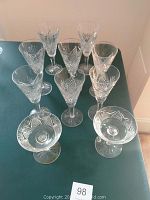 Top-down view of the 10 Waterford crystal glasses arranged in a group on a green surface showing various cut patterns and designs.