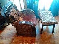 Wicker arm chair and matching foot stool on hardwood floor
