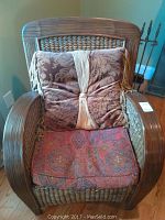 Front view of wicker and wood chair with red seat cushion and brown floral back pillow