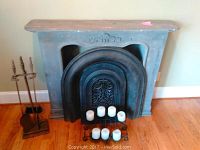 Faux wood fireplace mantle with metal cover and fireplace decor including candle holder and tools.