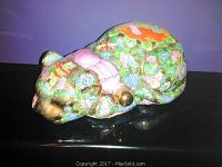 Ceramic cat figurine with floral pattern and gold accents taken from left side angle.