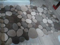 Full overhead view of the thick area rug showing the pebble pattern in various grey and brown shades.