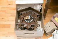 Cuckoo clock packed in a storage box with visible carved wood and clock face.