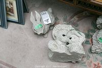 Photo showing a concrete rabbit figure and parts of two bear figures arranged on carpet.