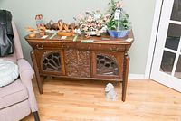 Full front view showing two top drawers, three lower doors with carved and glazed panels, turned legs.