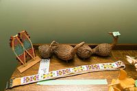 Wide shot of all six items on wood shelf showing snowshoes, birds, and beaded belt laid out