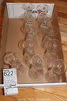 Top-down view of 11 clear wine glasses in a cardboard box, showing the bowl openings.