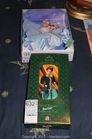 Two special edition Barbie dolls in original packaging, one with a green Victorian style dress box and the other in an open box with a doll in a blue gown.