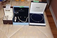 Three open jewelry boxes displaying multiple items including watches, pearl necklace, bracelet, earrings, and a silver-toned necklace.