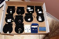 Overview of 15 jewelry pieces in a box: 12 rings in black pouches, necklace with pendant, and earrings in boxes