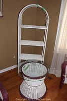 White wicker shelving stand with four shelves and arched top photographed from front and side angles.