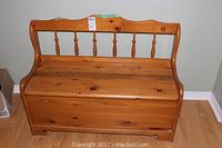 Front view of a pine Deacons bench showing the storage lid seat and spindle backrest.