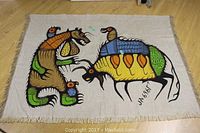 Full view of silk-screened wall hanging laid flat on floor, showing both animal figures and fringe edges