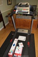 Front view of treadmill showing console, handrails and running belt with accessories on deck