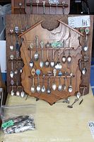 Full view of one wooden spoon rack with collector spoons hung on metal bars and loose spoons placed below the rack.