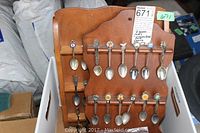 Two assembled wooden spoon racks with multiple assorted collector spoons featuring decorative handles and emblems.