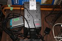 View of both APC Back UPS Pro power supply and D-Link Ethernet Broadband Router with cables on wooden surface.