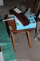 Overall view of wooden stool topped with knife box, grape lights box, wind chime tubes and hanger