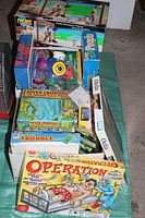 Photo showing assorted boxed board and party games including Operation, Trouble, River Crossing The Perilous Plane Puzzle, Ouija, People Trivia, Headbanz, Outburst and a Nerf toy box.