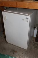 Full view of the Kenmore mini freezer showing white exterior with some wear marks and handle on the door.