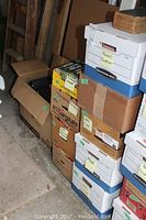 Stack of nine boxes, some labeled with author names and contents such as Pierre Burton and others, plus an old worn book on top