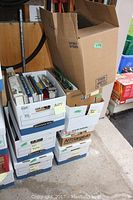 Seven stacked cardboard boxes filled with various books, showing some labeled as 'Art' and others packed tightly together.