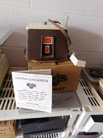 Side view of Glastar diamond glass grinder on top of its box with owner's manual displayed in front.