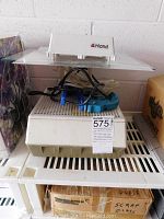 Photo of Inland glass grinder showing white base, glass surface, and blue hand tools on top with cords.