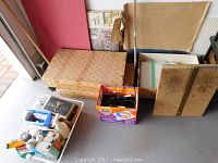 Overview of all items on floor: wire basket, cardboard boxes, wooden boards