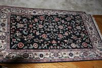 Photo showing the overall rug design with navy ground and floral motifs including central floral pattern and surrounding cream border with flowers.