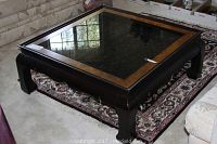 Full view of the square coffee table showing the wooden frame, dark finish, and glass top inset with lighter wood border.