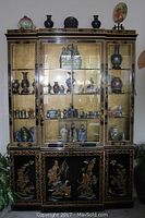 Full front view of the black lacquer curio cabinet with Asian gold Chinoiserie hand-painted designs, showing glass display sections and a base cabinet with painted doors.