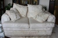Front view of the cream damask sofa with four pillows placed on it.