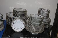 Stacked sets of dinnerware including plates, saucers, and bowls showing the quantity and general condition.