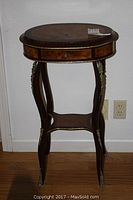 Full view of the oval gueridon table showing burlwood veneer top and ormolu bronze mounts on legs.