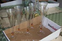 Six clear etched glass stemware glasses with grapevine motifs and amber stems in cardboard box.