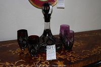 Five-piece Bohemian glass decanter and matching four glasses set displayed on a wooden table with inlay pattern.