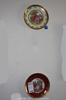 Two vintage JWK porcelain plates displayed on wall, showing their overall decorative style and size