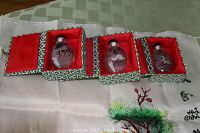 Three snuff bottles in individual decorative boxes with red interior lining on top of embroidered silk fabric featuring a crane and floral scene.