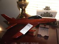 Side view of wooden aircraft model showing polished wood finish, black cockpit, and display stand.