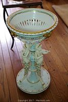 Full view of the porcelain plant stand showing open basket top and cherub supports