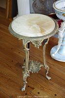 Full front view of ornate gilded cast iron table with round marble top.