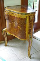 Full front and right-side view of triangular bombe-form vanity showing curved sides, marquetry panels and gilt bronze trim.