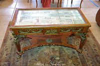 Front view of the rectangular shadow box table with glass top showing interior display area and ornate trim on rug.