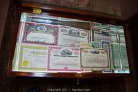 Wooden display case holding multiple stock certificates