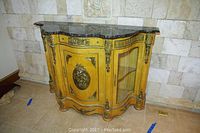 Front overview of console server showing serpentine silhouette, wood veneer body, metal appliques and marble top.