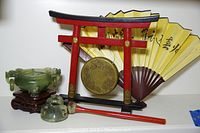 Wide shot showing the jade bowl on wooden stand, brass gong, striker, folding fan, and Torii gate stand