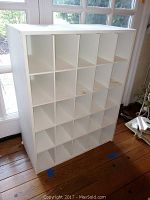 Front view of white laminate shoe shelf showing 20 cubby compartments.