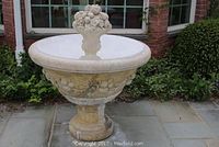 Full front view of concrete fountain on stone patio, showing bowl, pedestal, finial